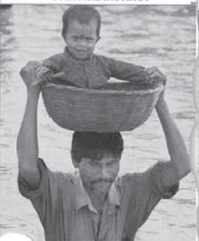 SURVIVAL INSTINCTWater Woes : A father carries his son to safety as he writes through floodwater, after a three-day spell of body rain in Dhantala village, near Sitiguri